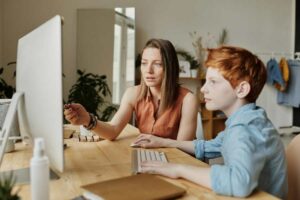 Home Tutor helping a boy on the computer