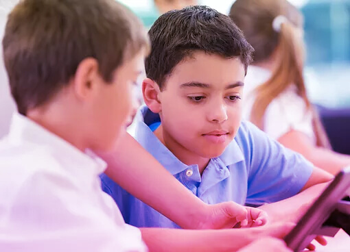 Two school boys sharing a tablet in a school environment.